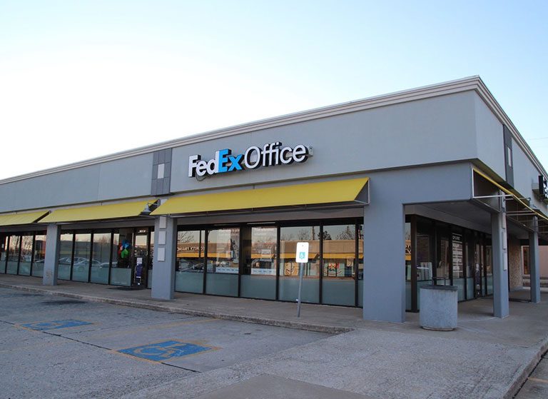 FedEx Office storefront with yellow awnings in a shopping plaza.