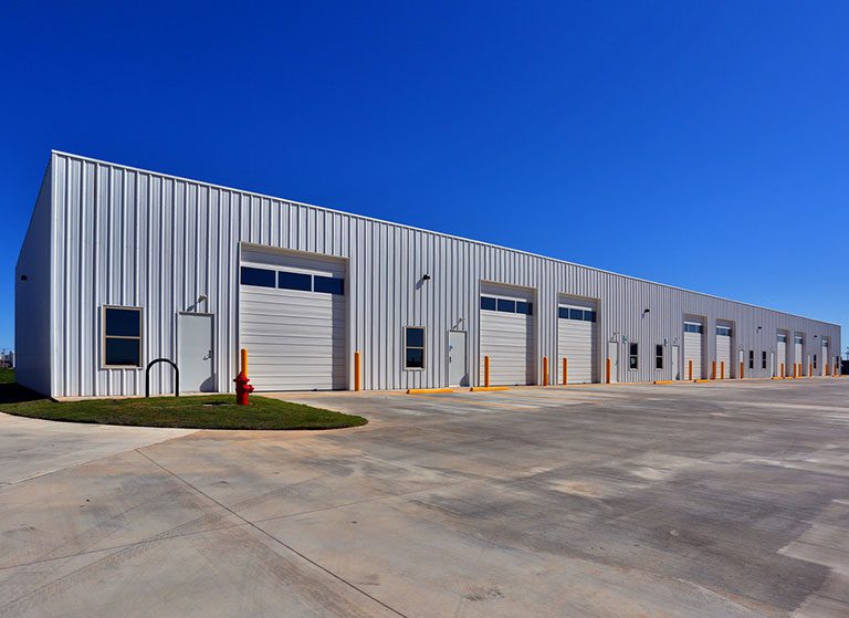 A modern industrial warehouse with multiple loading docks under a clear blue sky.
