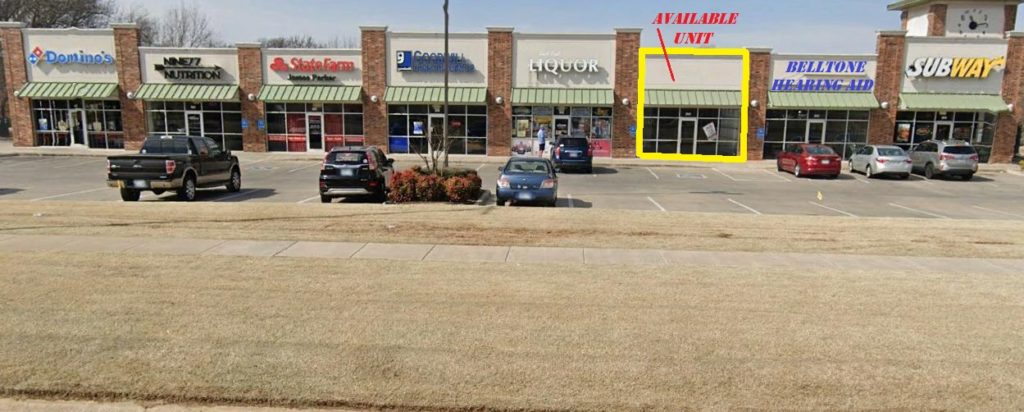 Parking lot with a few cars and storefronts including a retail exit.