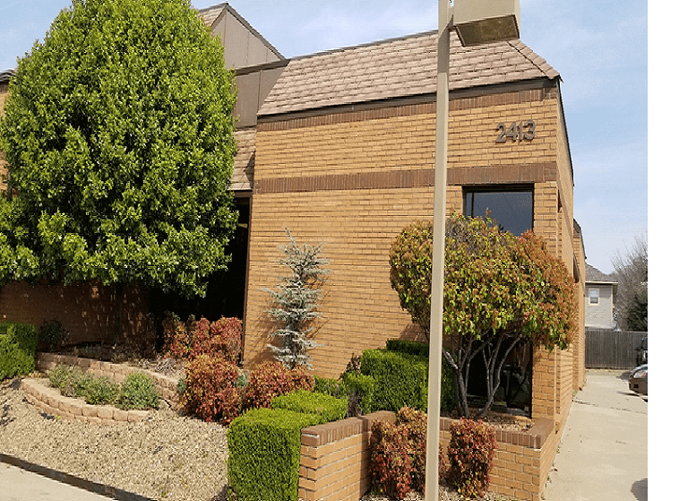 Modern brick building with trees and a street lamp in front.