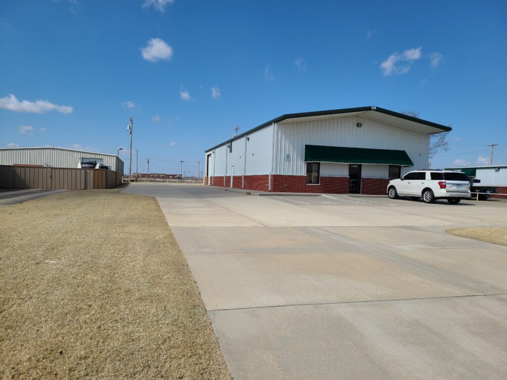 A large warehouse with a white truck parked outside under a clear blue sky.