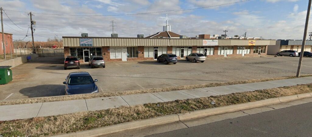 Single-story motel with parked cars in front under a cloudy sky.