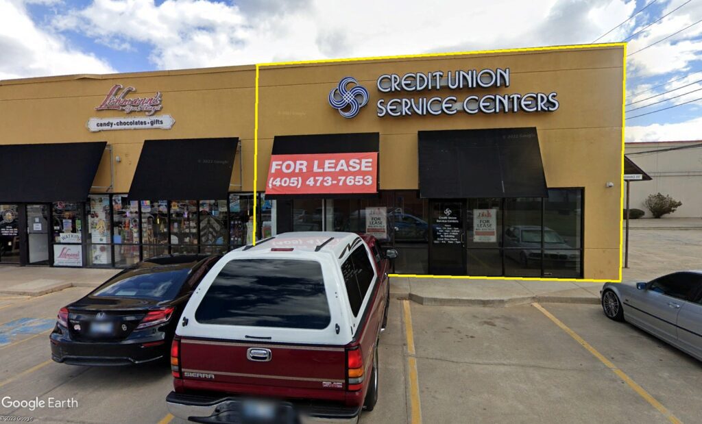 A storefront with a For Lease sign and a parked red and white SUV.